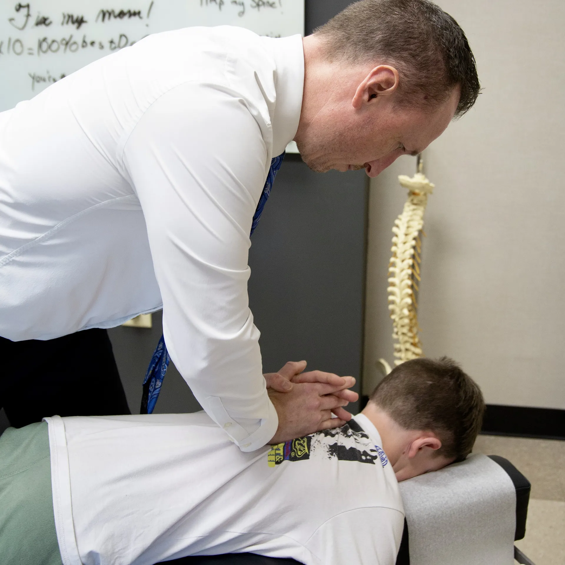 Dr. Charlie Gray adjusting the upper back of a young man lying face-down