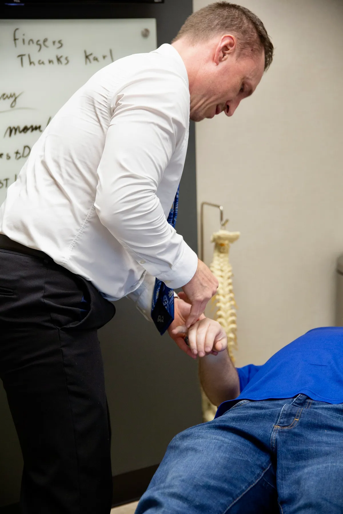 Dr. Charlie Gray holding the arm of a patient lying face-down during treatment