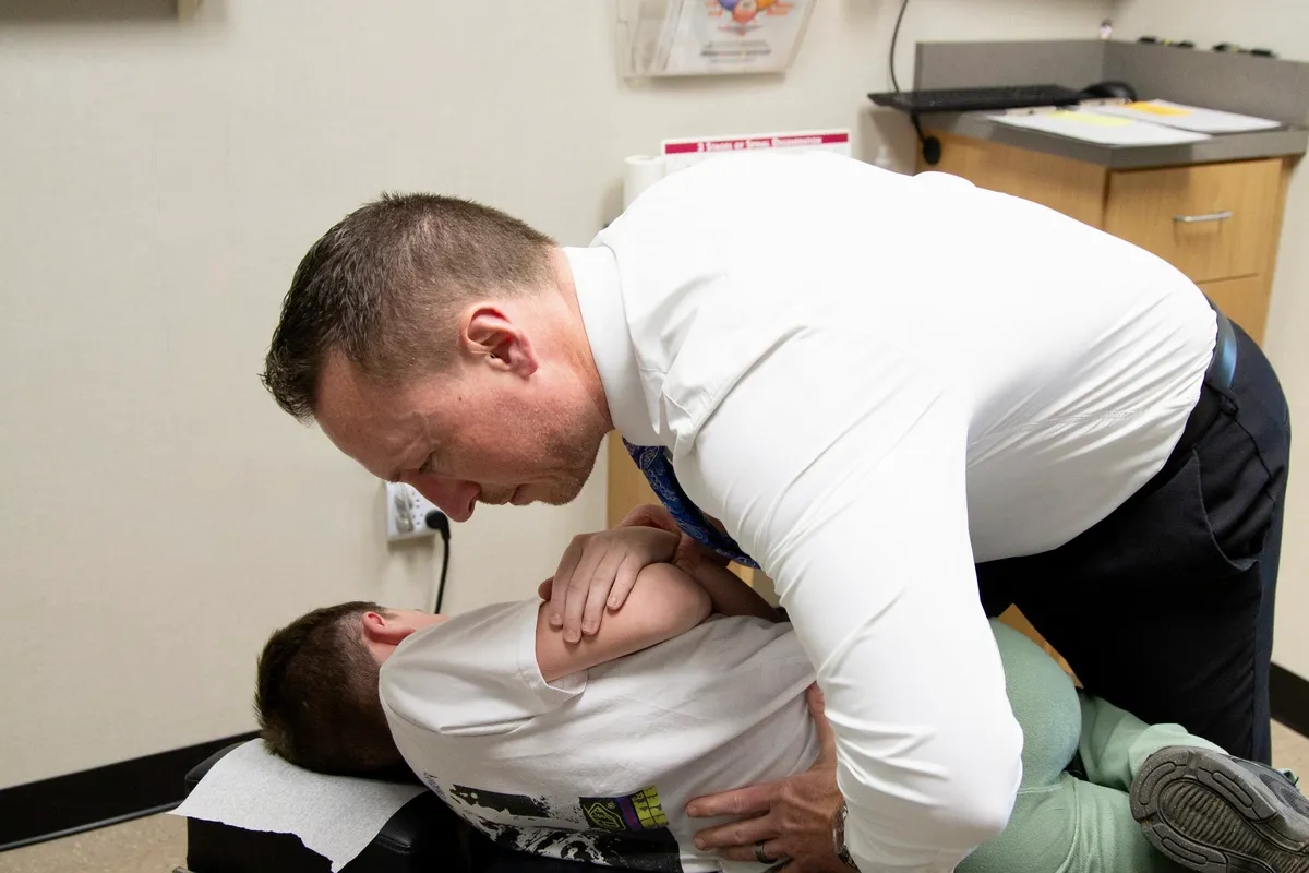 Dr. Charlie Gray performing a side-lying adjustment on a young patient in a white T-shirt