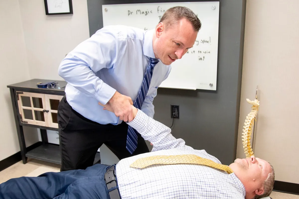 Dr. Charlie Gray stretching the arm of a patient lying face-up on the table