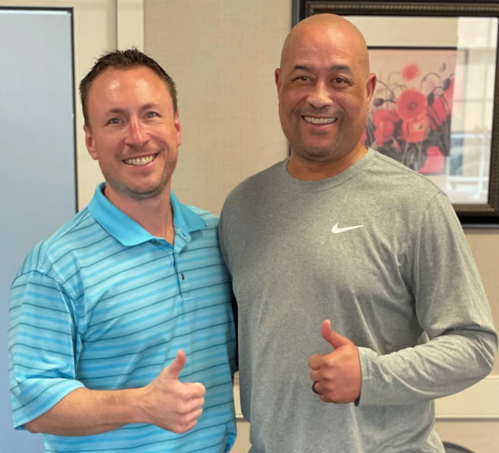Chiropractor in a striped polo and a patient both giving a thumbs-up