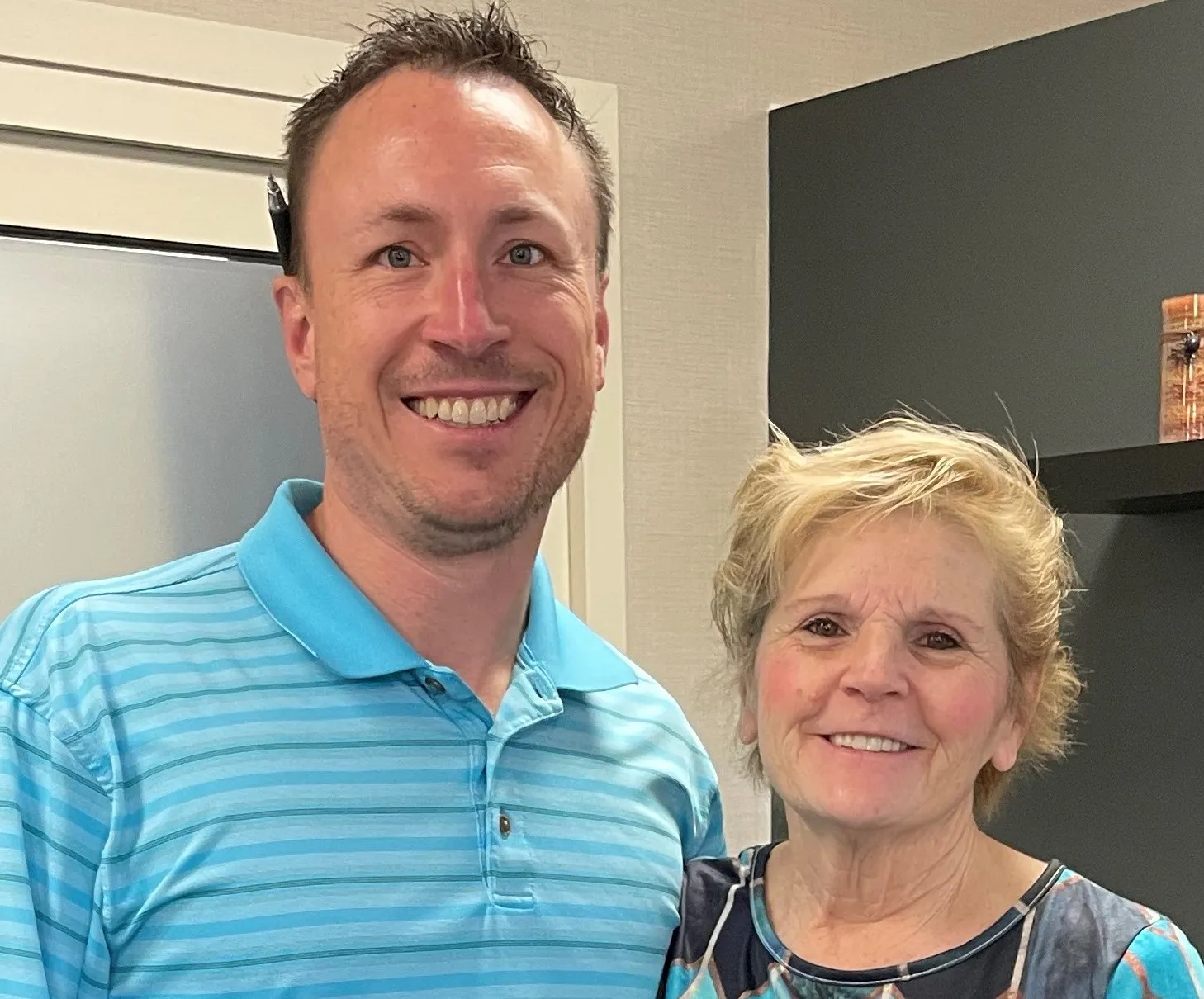 Close-up of a chiropractor in a blue striped polo and a smiling patient
