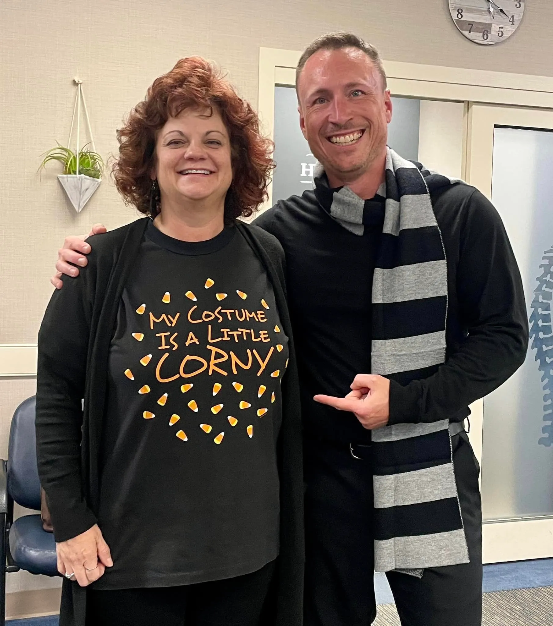 Chiropractor in a striped scarf with a patient wearing a candy-corn costume T-shirt