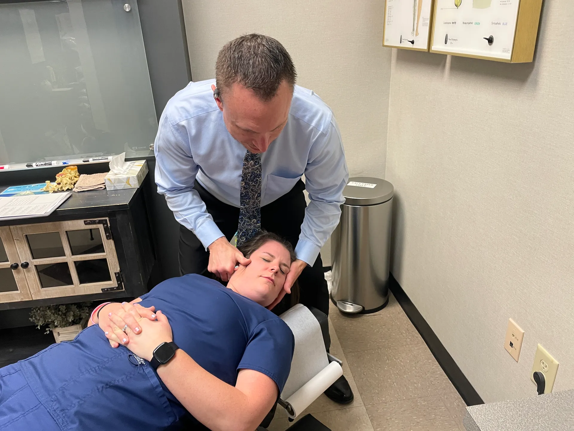 Dr. Charlie Gray adjusting the neck of a young man lying face-up on the table