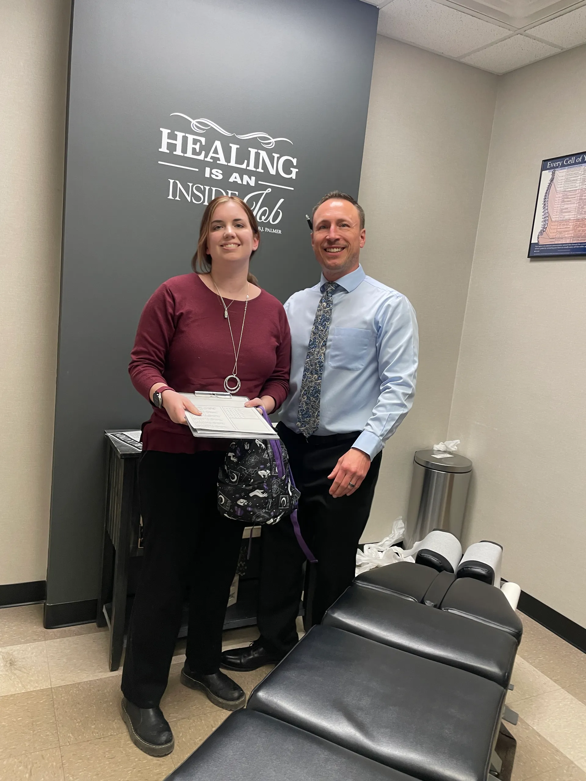Dr. Charlie Gray with a patient holding an envelope beside a "Healing is an inside job" wall