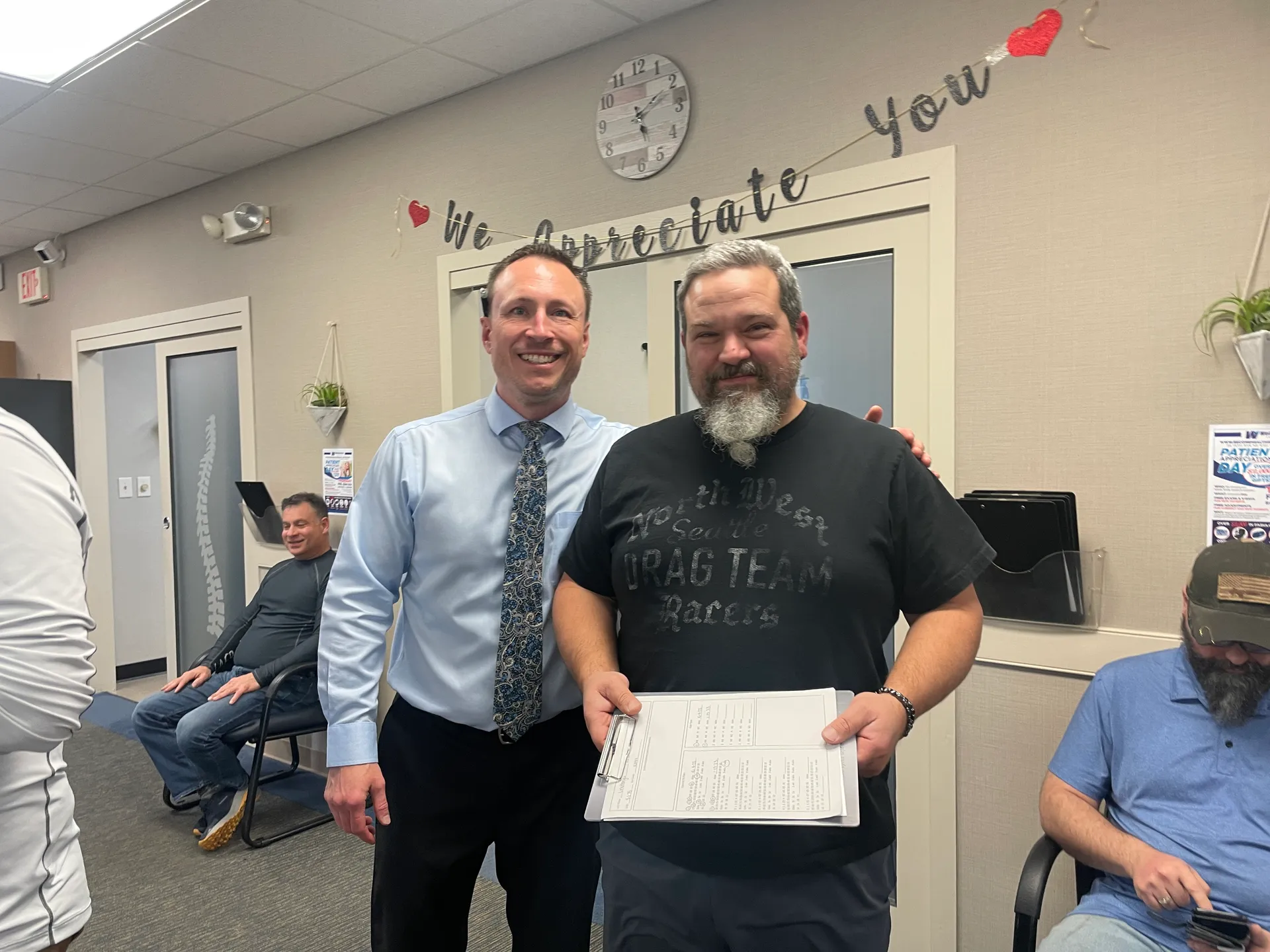 Dr. Charlie Gray with a bearded patient holding paperwork in the clinic lobby