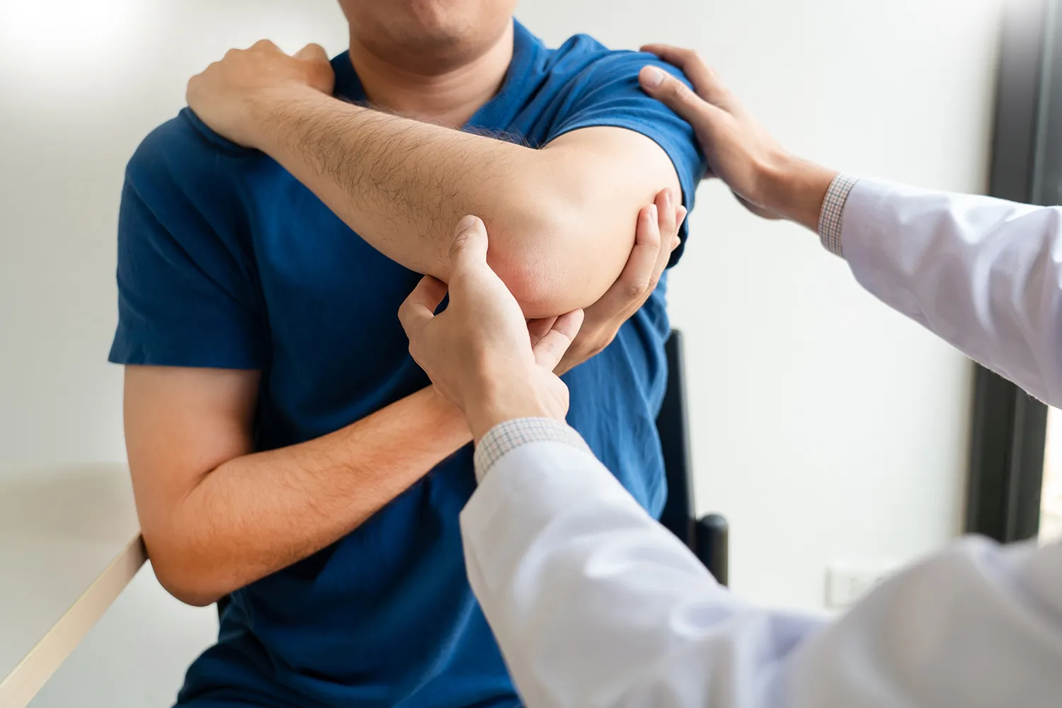 Chiropractor examining a patient’s shoulder and elbow