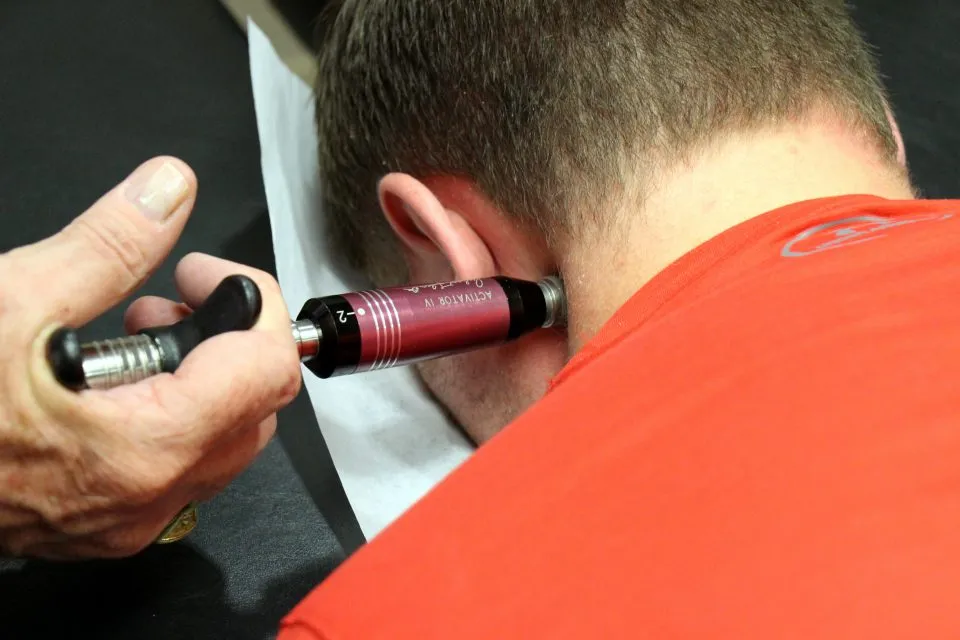 Activator adjusting instrument placed on the back of a man's neck