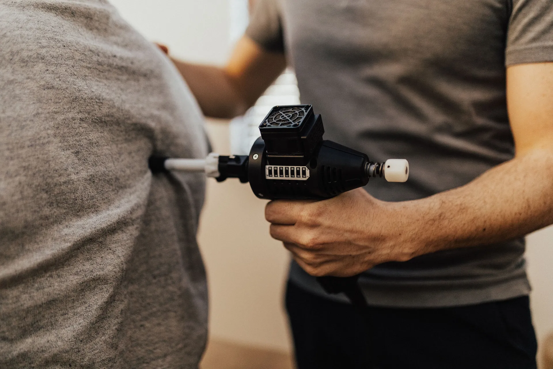 Practitioner pressing an ArthroStim adjusting instrument against a patient's back