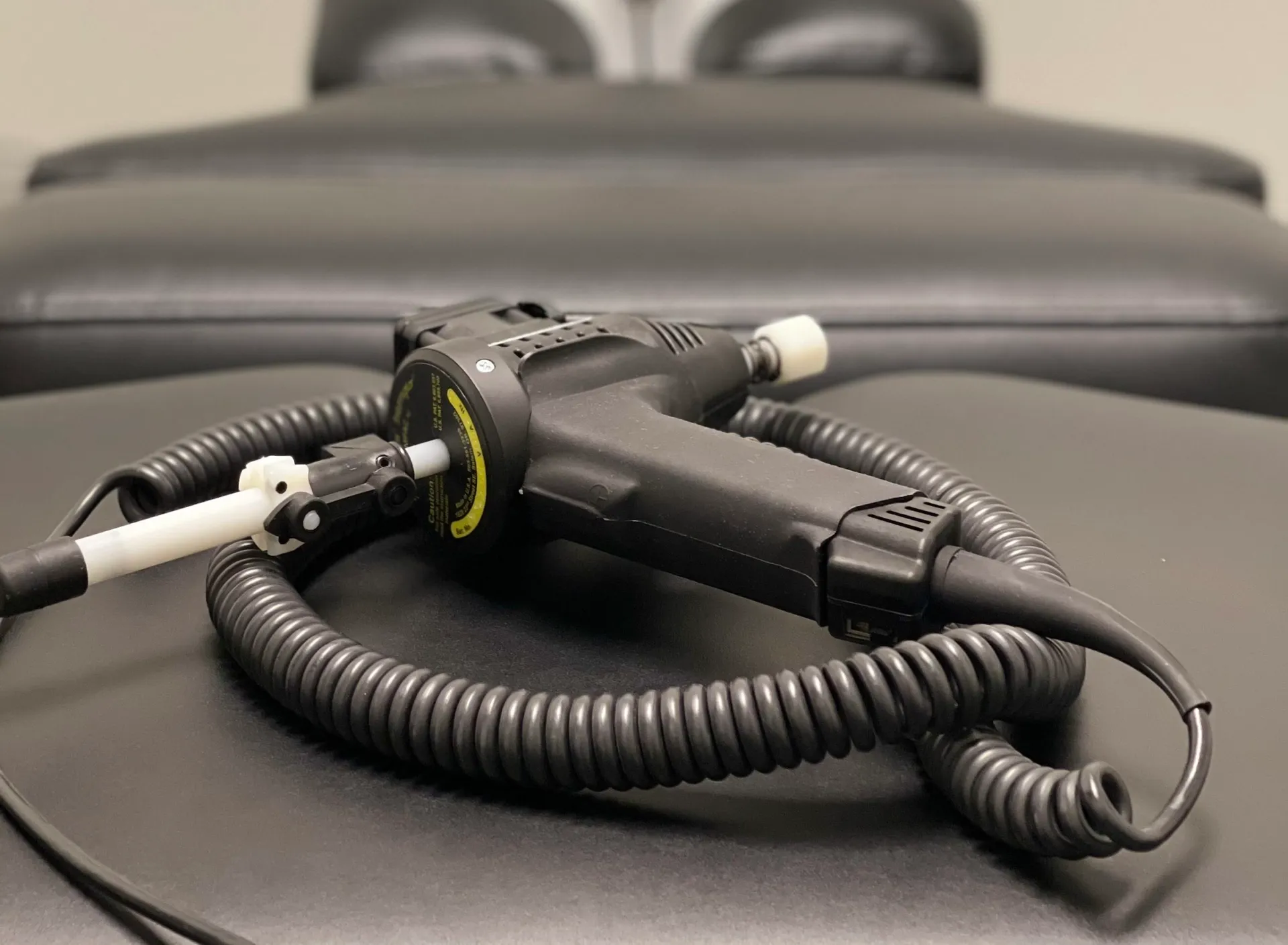 ArthroStim adjusting instrument with a coiled cord resting on a treatment table