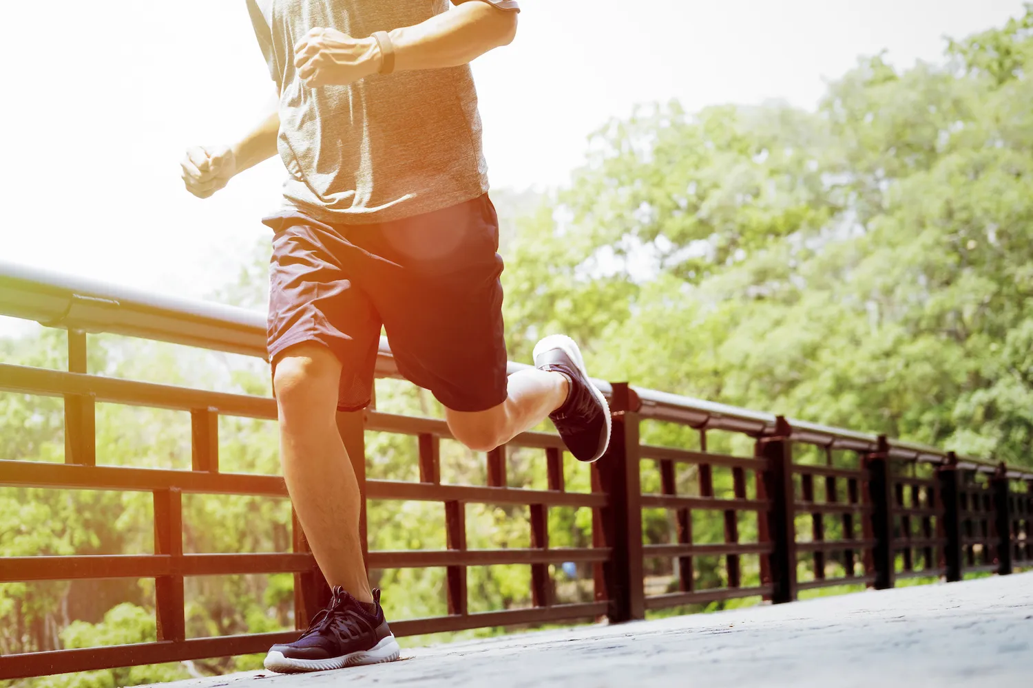 Man running outdoors along a railing on a sunny day