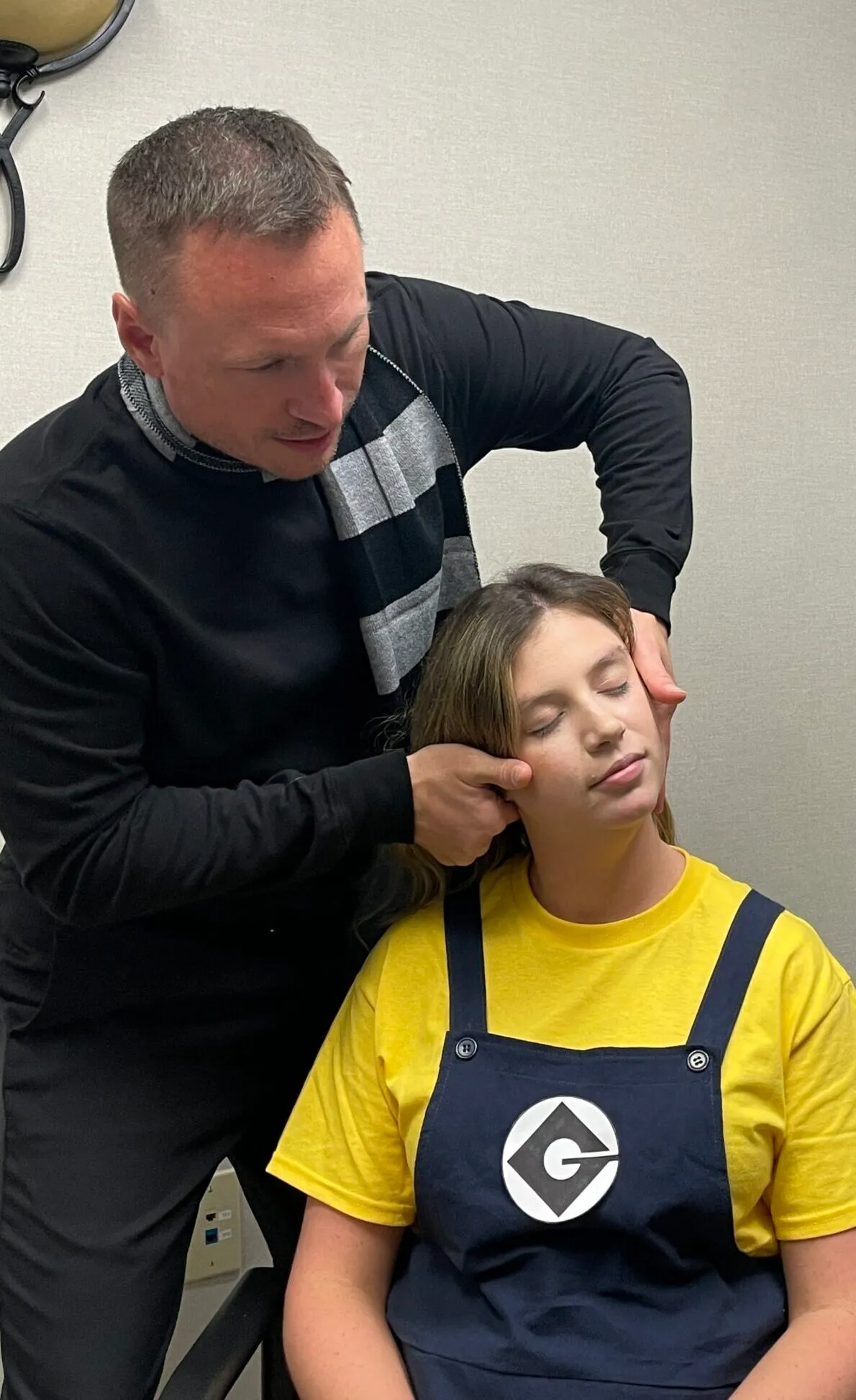 Chiropractor holding a seated young patient's head to adjust her neck