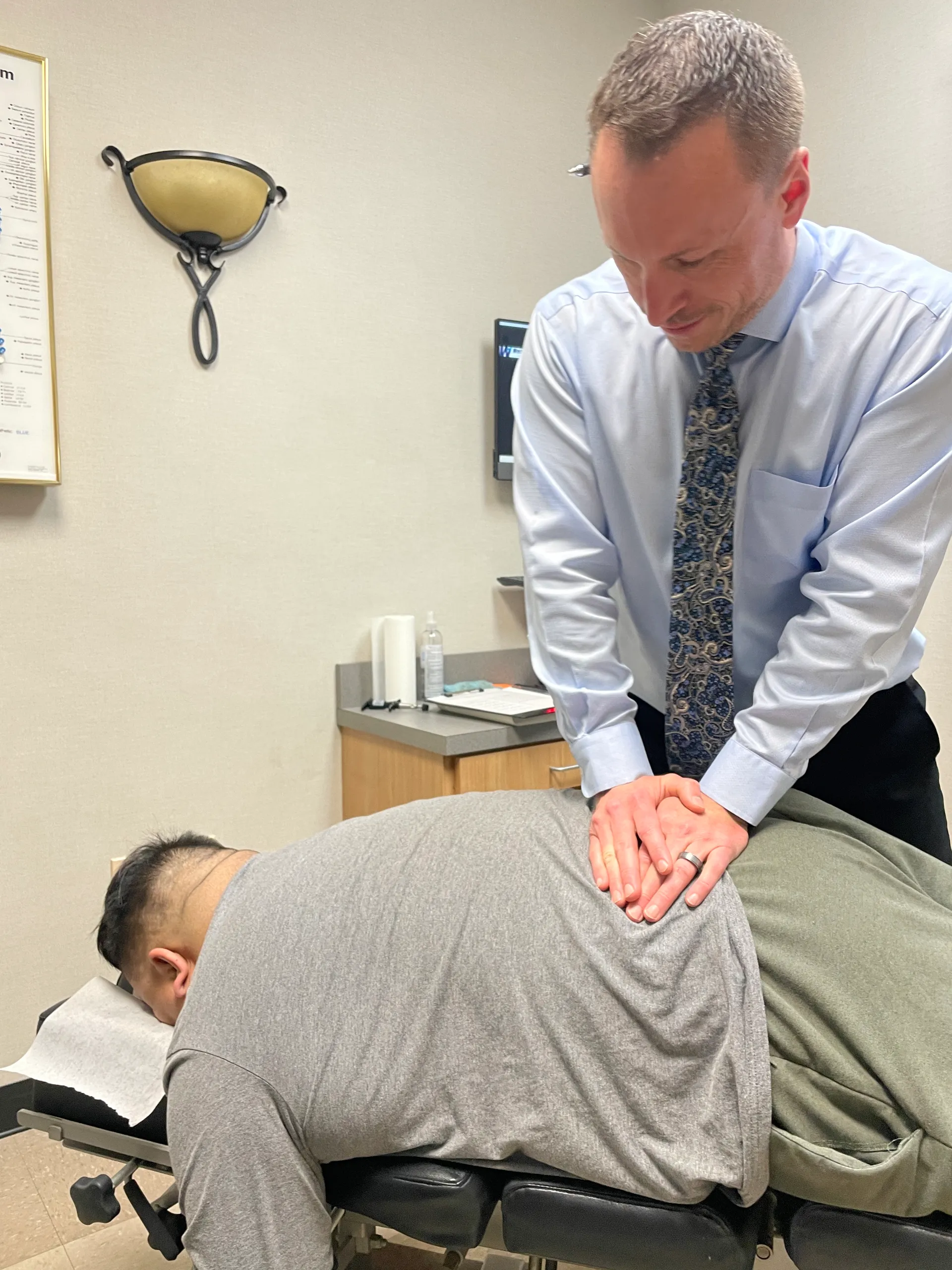 Dr. Charlie Gray applying pressure to a male patient's lower back on a chiropractic table