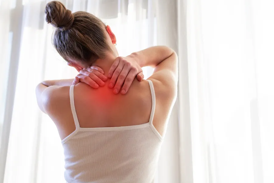Woman rubbing the back of her neck, with redness marking the area of pain