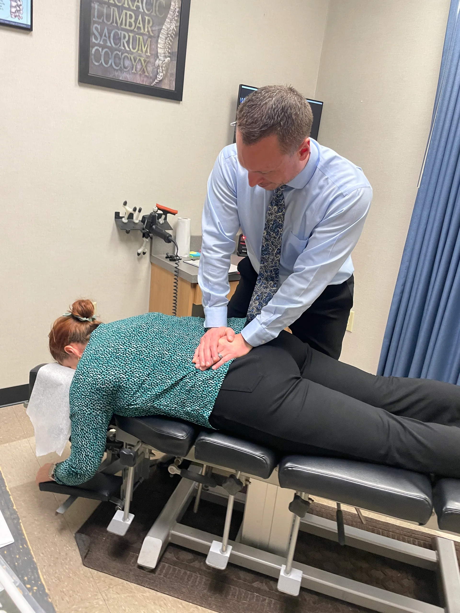 Dr. Charlie Gray adjusting the lower back of a female patient lying face-down