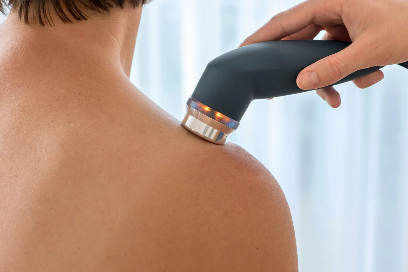 Ultrasound therapy probe held against a patient's bare shoulder