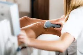 Clinician applying an ultrasound therapy probe to a patient's shoulder