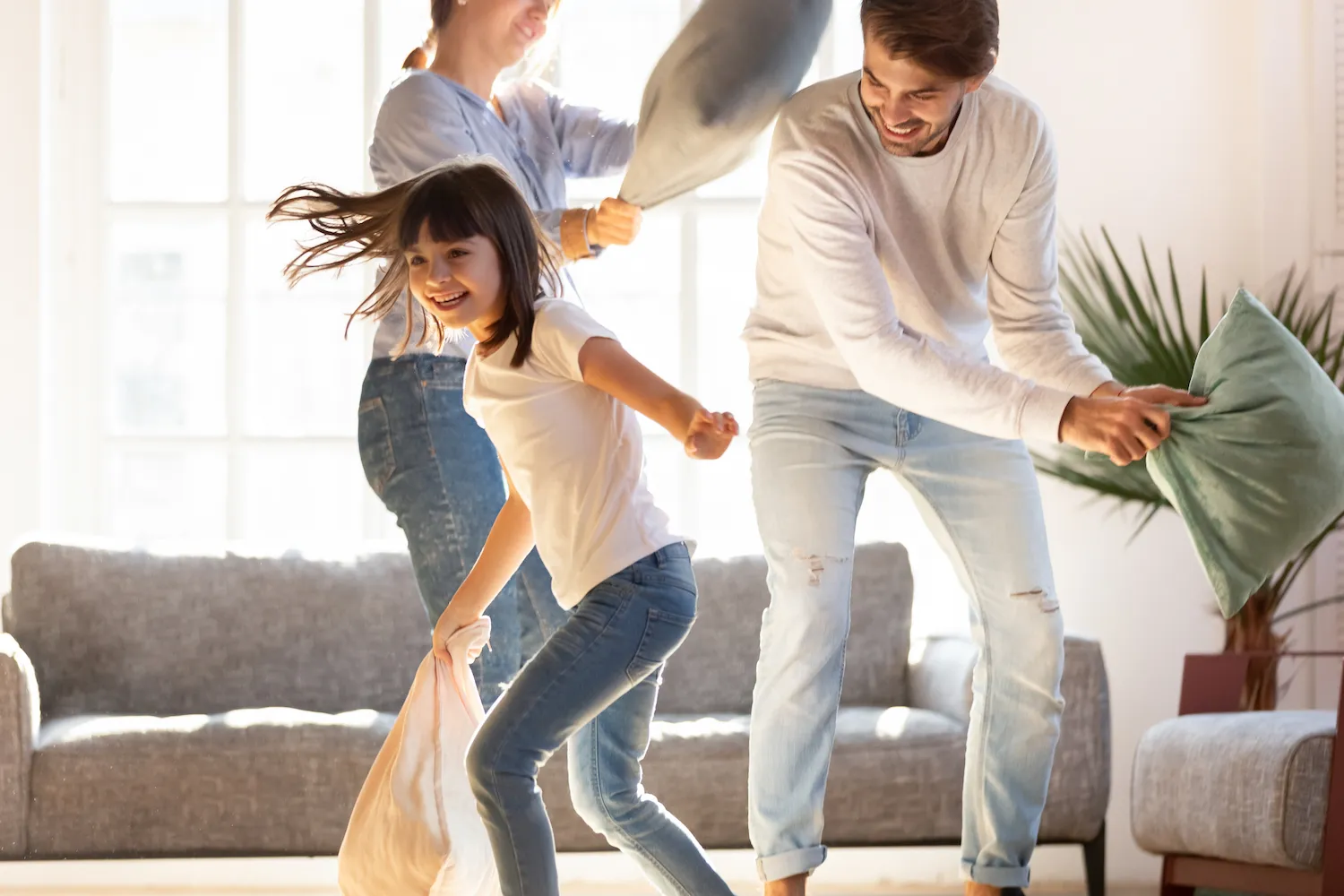 Girl and her parents having a playful pillow fight in the living room