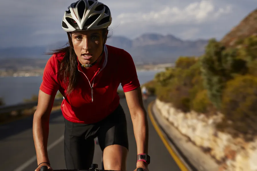 Female cyclist in a helmet riding on a coastal road