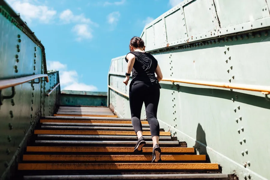 Woman running up a long outdoor staircase