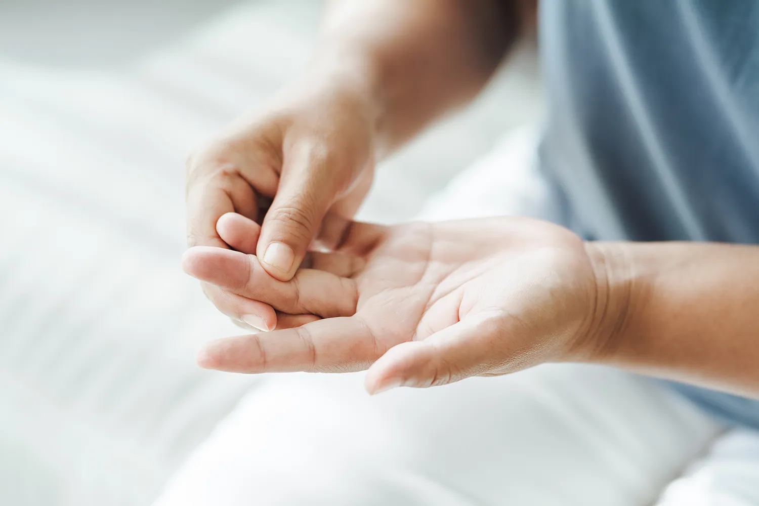 Person pressing a thumb into the palm of their other hand