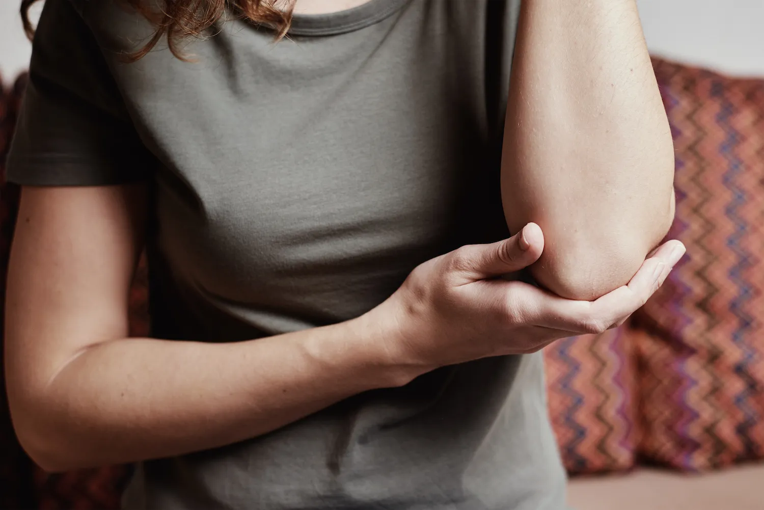 Close-up of a woman cupping her sore elbow in her hand