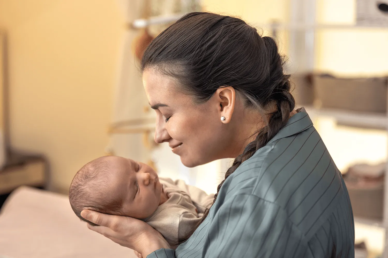 Mother smiling as she cradles her sleeping newborn