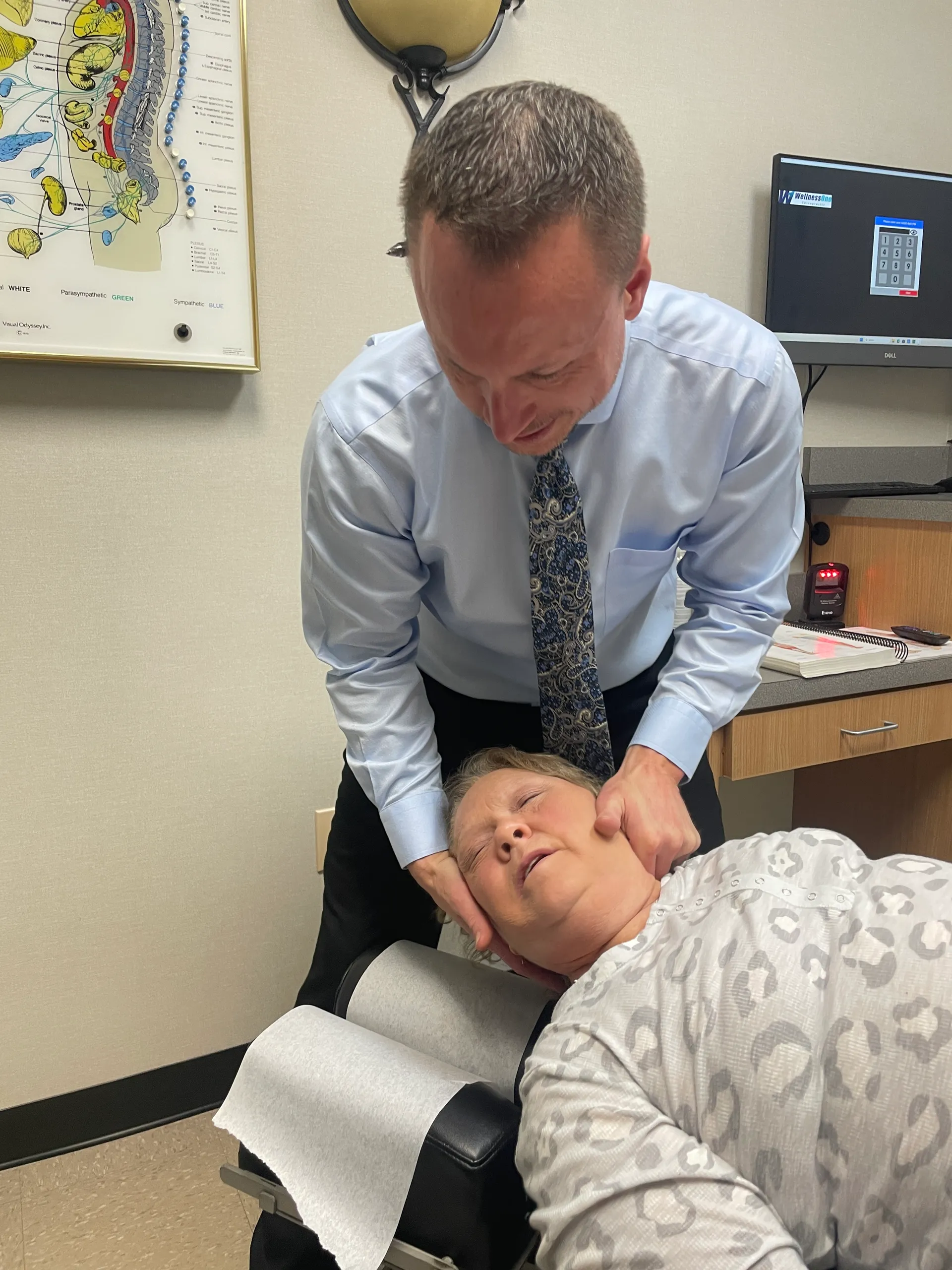 Dr. Charlie Gray adjusting the neck of an older woman lying face-up on the table