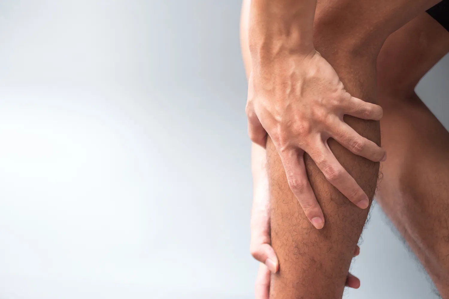 Close-up of a hand gripping a sore leg muscle