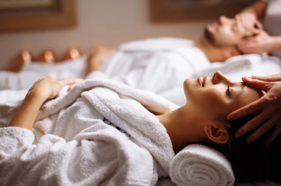 Couple in robes relaxing during a face and head massage at a spa
