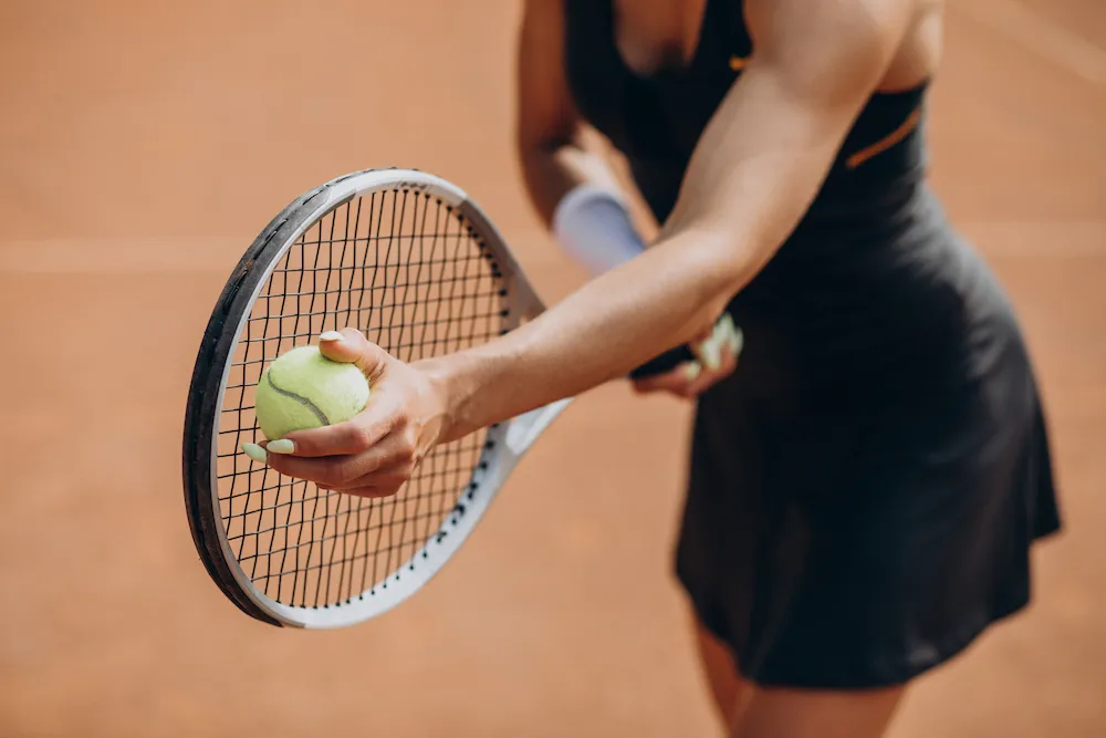 Woman preparing to serve with a tennis racket and ball